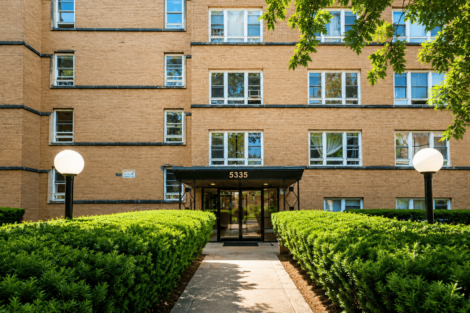 Landscaped entrance to a brick multifamily property