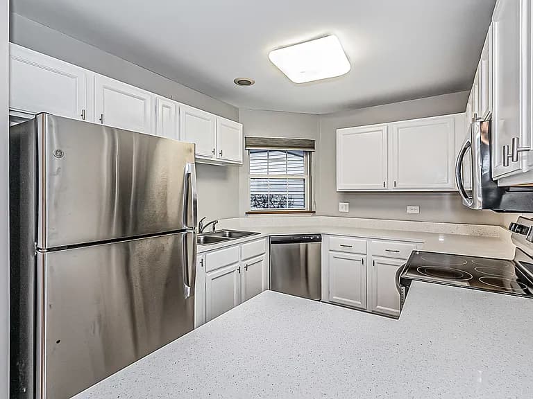 Kitchen work area with white cabinetry and stainless steel appliances