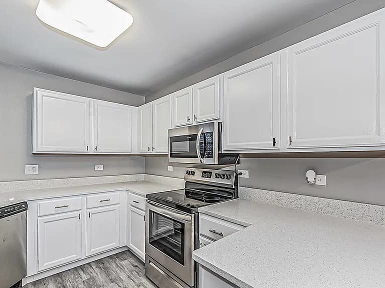 Quartz countertops, white cabinets, microwave, and range in the kitchen