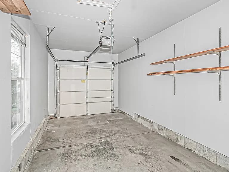 Attached one-car garage with shelving and pull-down attic access